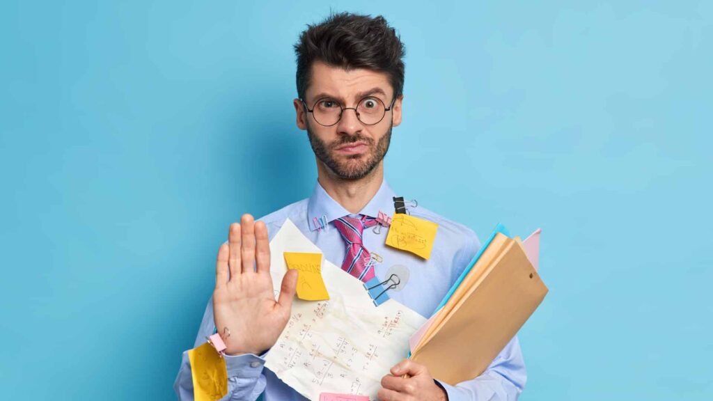 A man holding a document file with too many sticky notes looks confused on how do you plan to achieve your goals.